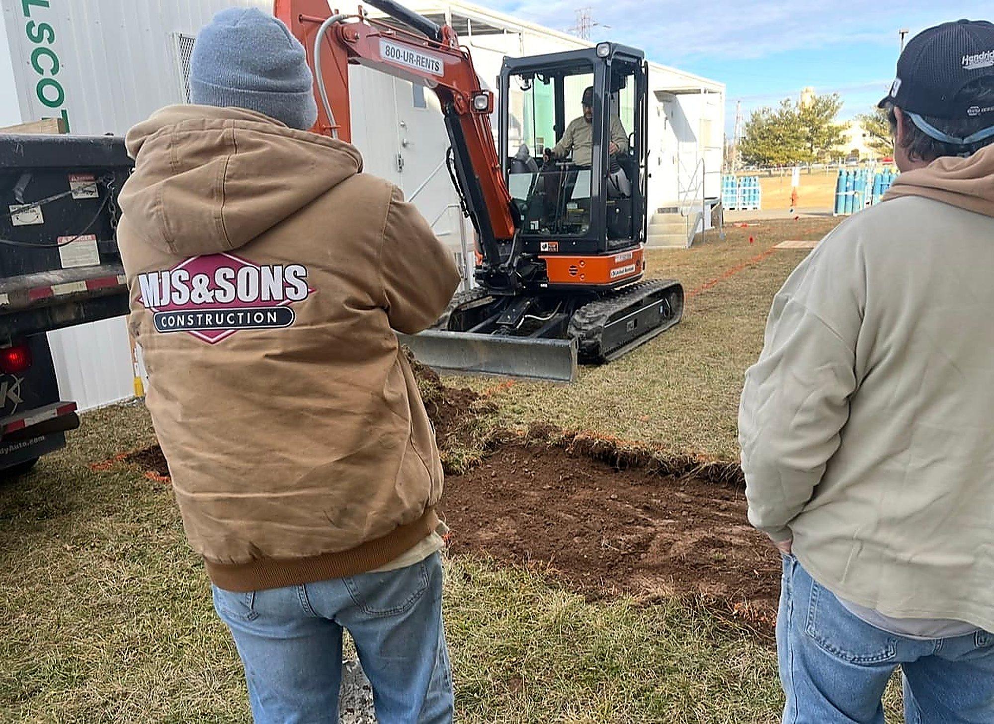 MJS & Sons Construction crew on a site excavation, company logo on the crew jacket